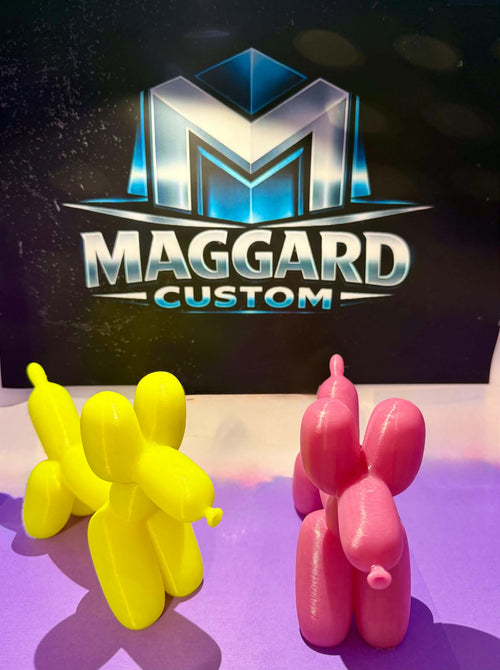 3D printed balloon animal dog figurines in bright yellow and pink with glossy finish displayed in front of Maggard Custom logo