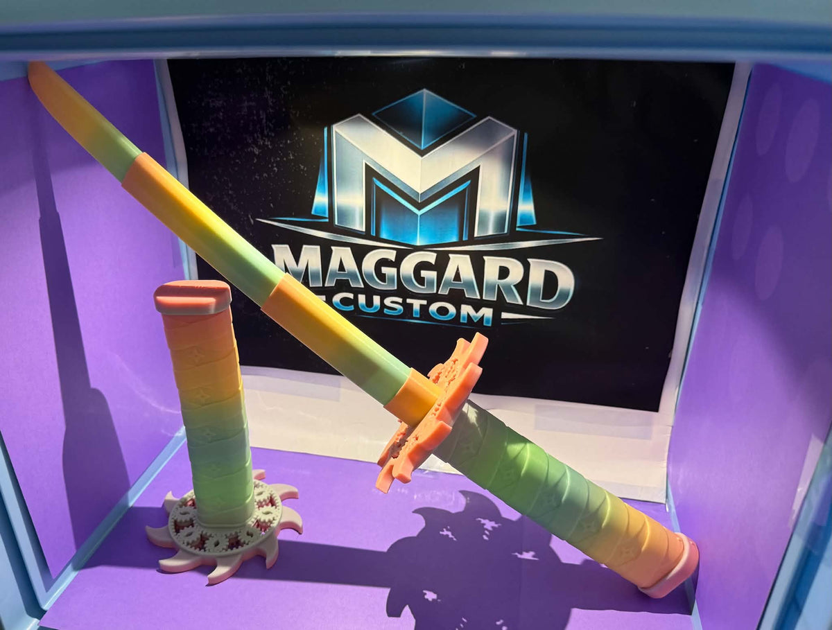 3D printed full-size collapsible katana in rainbow gradient with wrapped grip and shuriken display stand, shown in front of Maggard Custom logo