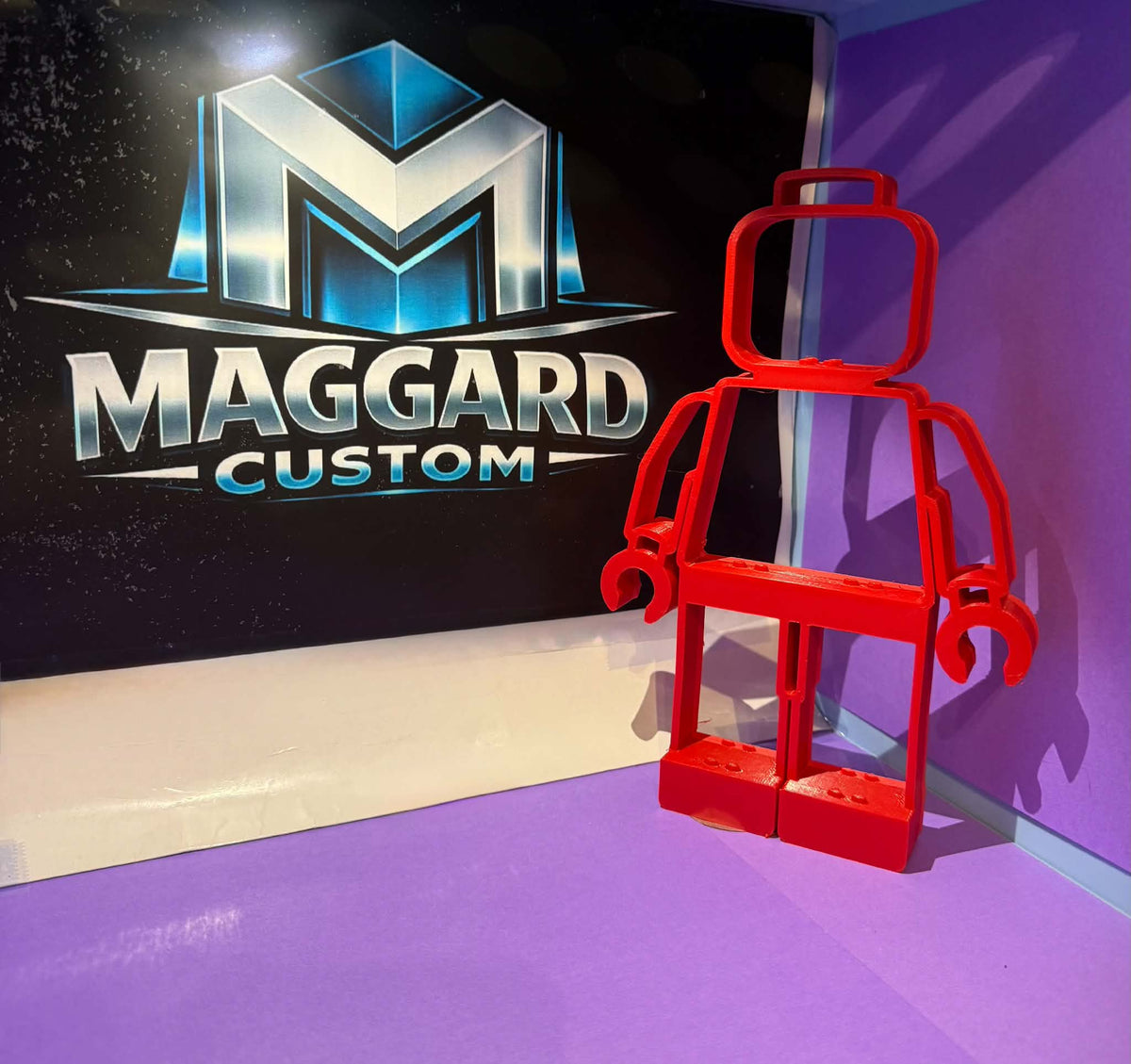3D printed red brick toy figure silhouette open-frame display shelf with built-in ledges displayed in front of Maggard Custom logo
