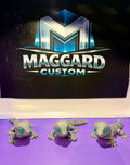 3D printed articulated baby dragon gecko figurines in stone gray with teal gemstone eyes shown in three different poses displayed in front of Maggard Custom logo