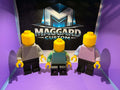3D printed brick toy figures in gray, teal, and pink two-tone color combinations displayed in front of Maggard Custom logo