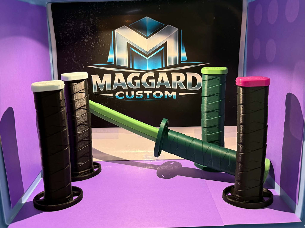 3D printed mid-size katanas with wrapped grips and display stands in black, green, and pink color combinations displayed in front of Maggard Custom logo