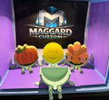 3D printed sponge scrubby holders with articulated legs and interchangeable face plates showing pumpkin, smiley face, and turkey designs displayed in front of Maggard Custom logo