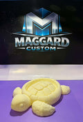 3D printed cream yellow turtle soap dish with detailed shell pattern and four flippers displayed in front of Maggard Custom logo