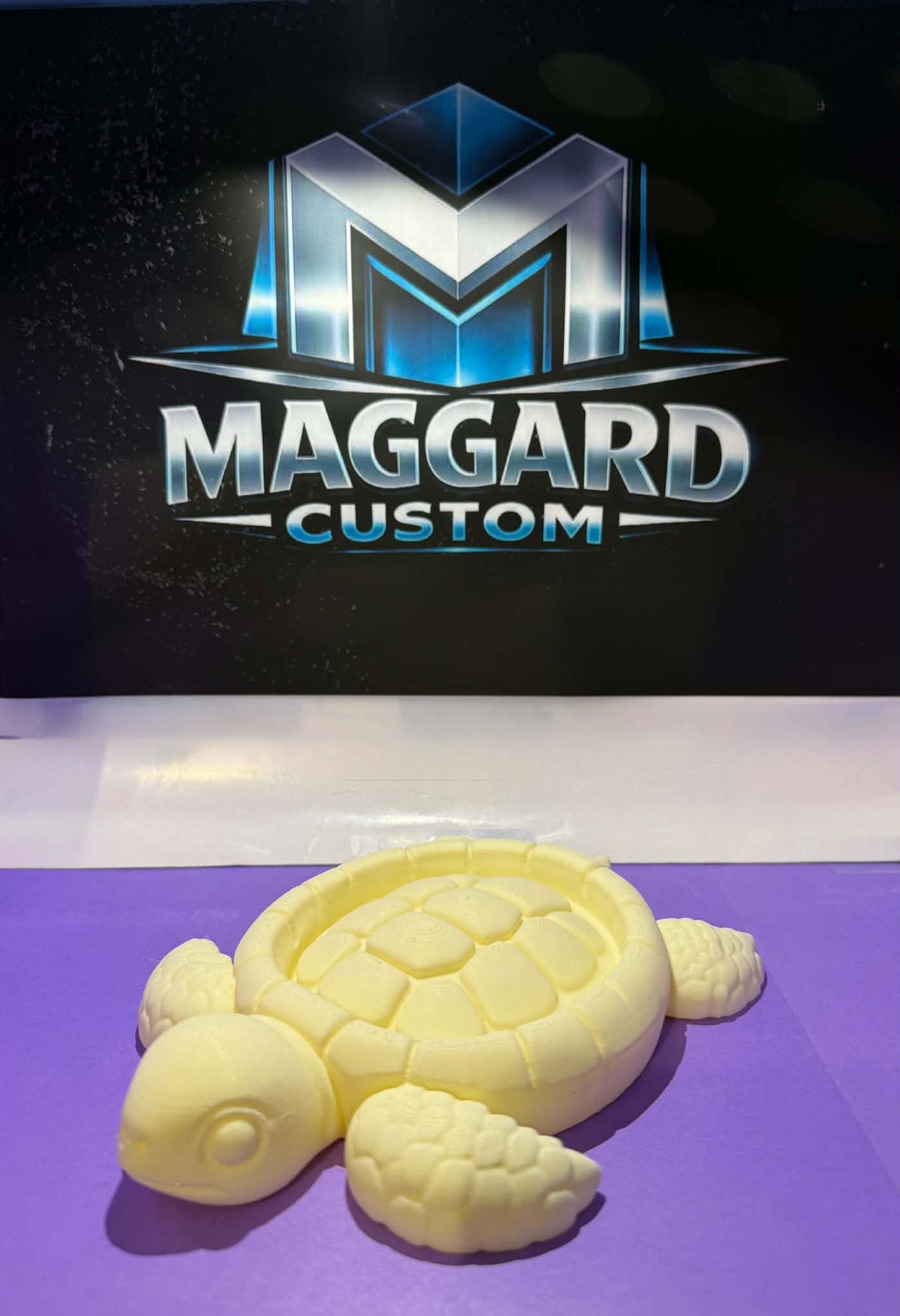 3D printed cream yellow turtle soap dish with detailed shell pattern and four flippers displayed in front of Maggard Custom logo